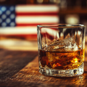 Glass of bourbon on a wooden table with an American flag in the background