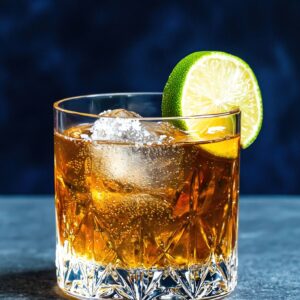 Glass of reposado tequila with lime on the rim.