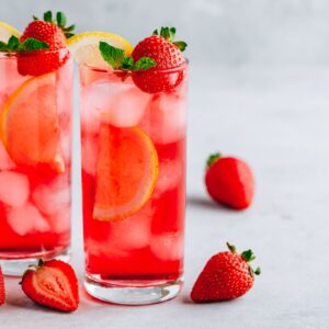 Two glasses filled with a strawberry lemonade vodka cocktail with strawberries.