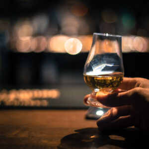 A hand holding a bourbon tasting glass