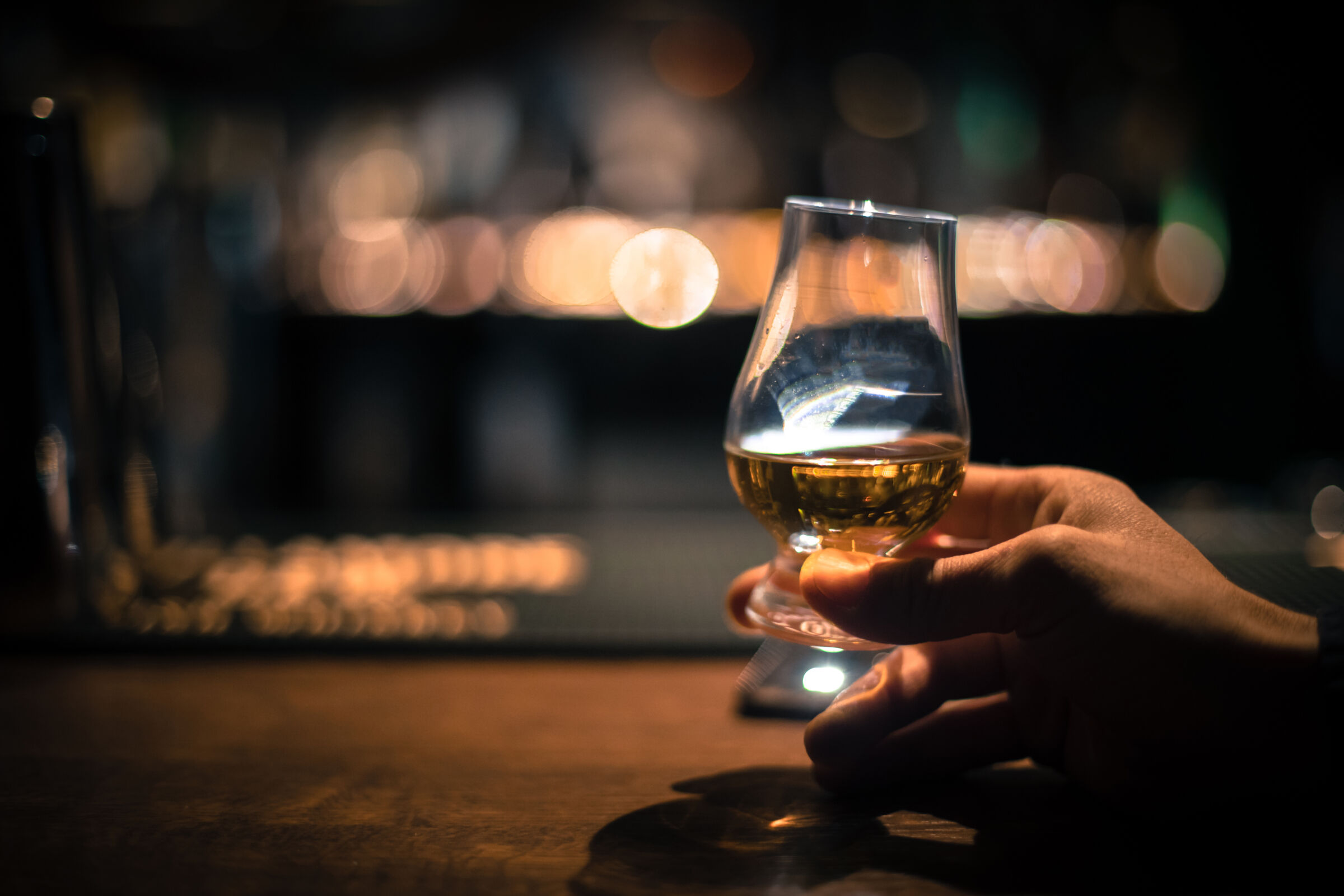 A hand holding a bourbon tasting glass