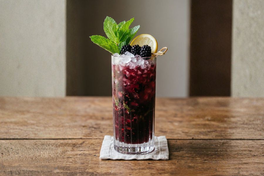 Tall glass filled with blackberry bourbon smash recipe from greensboro abc